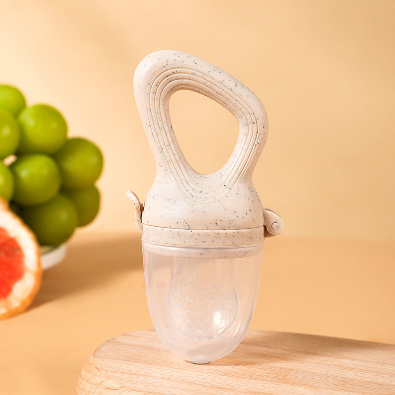 A silicone baby fruit feeder with a soft textured handle and clear feeding chamber, displayed on a warm peach background with fresh fruit.